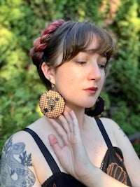 a woman with tattoos wearing a pair of earrings