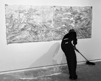 a woman cleaning a painting on a wall