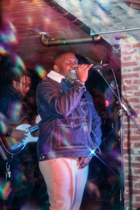 a man in a jacket singing into a microphone
