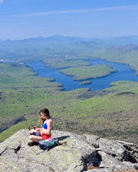 a woman sitting on top of a mountain with a laptop