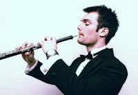 a man in a tuxedo playing a flute