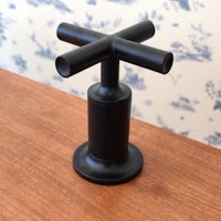 a black toilet brush holder on top of a wooden table