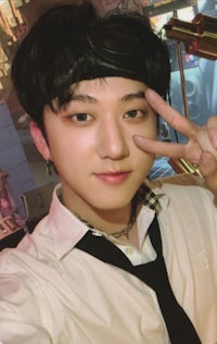 a young man in a white shirt and tie making a peace sign
