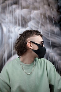 a man wearing a face mask in front of a mural