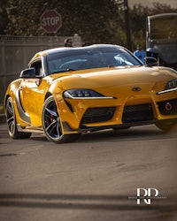 a yellow toyota supra driving down the street
