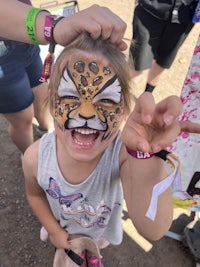 a little girl with a face painted like a leopard