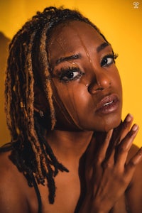 a woman with dreadlocks posing with her hands on her face