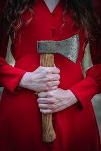 a woman in a red dress holding an axe