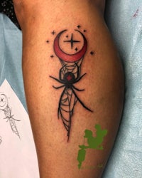 a woman's leg with a tattoo of a spider and a crescent moon