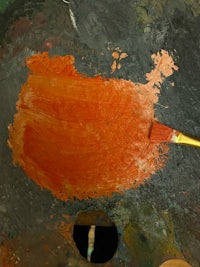 orange paint on a palette with a brush