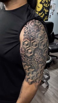 a man with a geometric tattoo on his sleeve