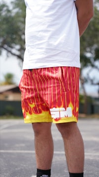 a man wearing red and yellow shorts standing on a basketball court