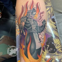 a tattoo of a ninja with flames on his arm