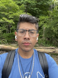a man in glasses is taking a selfie in the woods