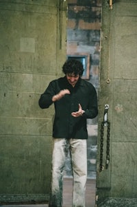 a man in a black shirt standing in front of a door