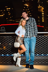 a couple posing for a photo in front of a city skyline