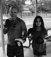 a man and a girl standing next to each other with boxing gloves
