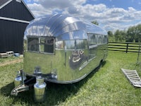 a silver airstream trailer parked in the grass
