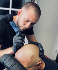 a man is getting a tattoo on his head