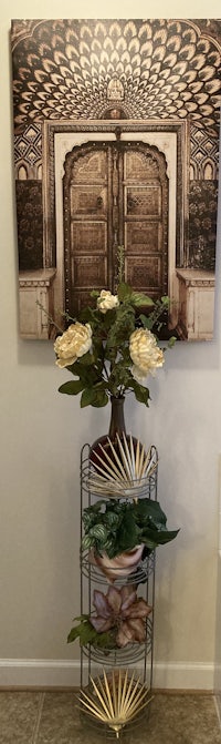 a metal plant stand with a painting in front of it