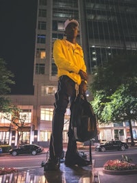 a man in a yellow jacket standing in front of a building at night