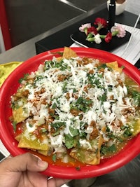 a person holding a red plate with nachos on it