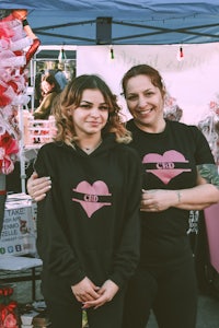 two women posing for a photo at a valentine's day market