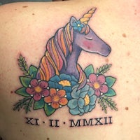 a woman's back tattoo with a unicorn and flowers