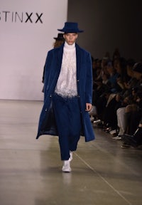 a man wearing a blue coat and hat on the runway