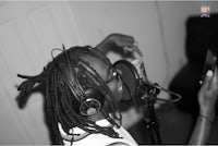 a black and white photo of a person with dreadlocks in a recording studio