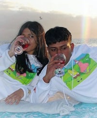 two people sitting on a beach with glasses of wine