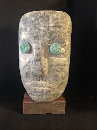 a sculpture of a head with turquoise eyes