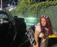 a woman leaning against a car at night