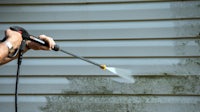 a man using a pressure washer to clean a house