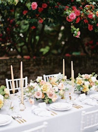 a table set with white chairs and yellow flowers