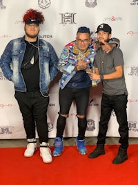 three men posing for a photo on a red carpet