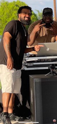 two men standing next to a dj booth