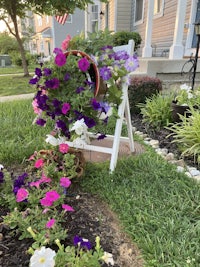 a white chair with purple flowers on it in front of a house