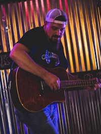 a bearded man playing an acoustic guitar