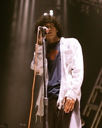 a man with curly hair singing into a microphone