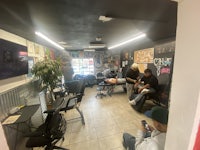 a group of people sitting in chairs in a tattoo shop