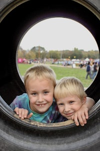 two young boys peeking out of a tire