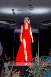 a woman in a red dress walking down a runway