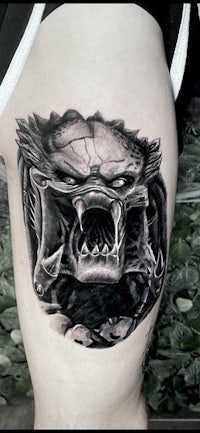 a black and white tattoo of a monster with teeth