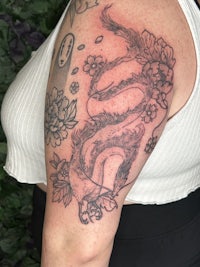 a woman's arm with a tattoo of a snake and flowers