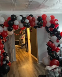 a balloon arch decorated with black, red and white balloons