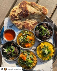 four bowls of indian food on a wooden table