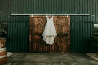 a wedding dress hanging on a barn door
