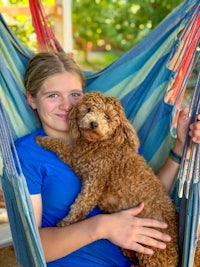 a girl holding a dog in a hammock