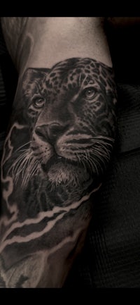 a black and grey tiger tattoo on a man's leg